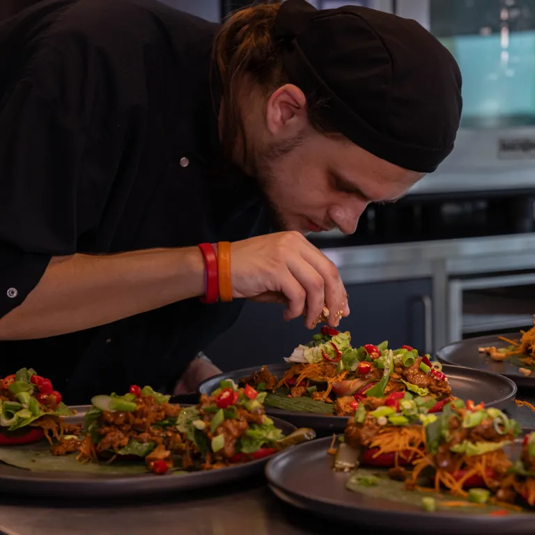 Robin werkt geconcentreerd aan een gerecht.