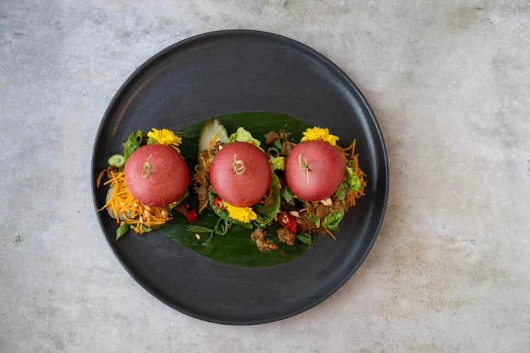 Een door Robin gemaakt gerecht met drie roze broodjes op een zwart bord.